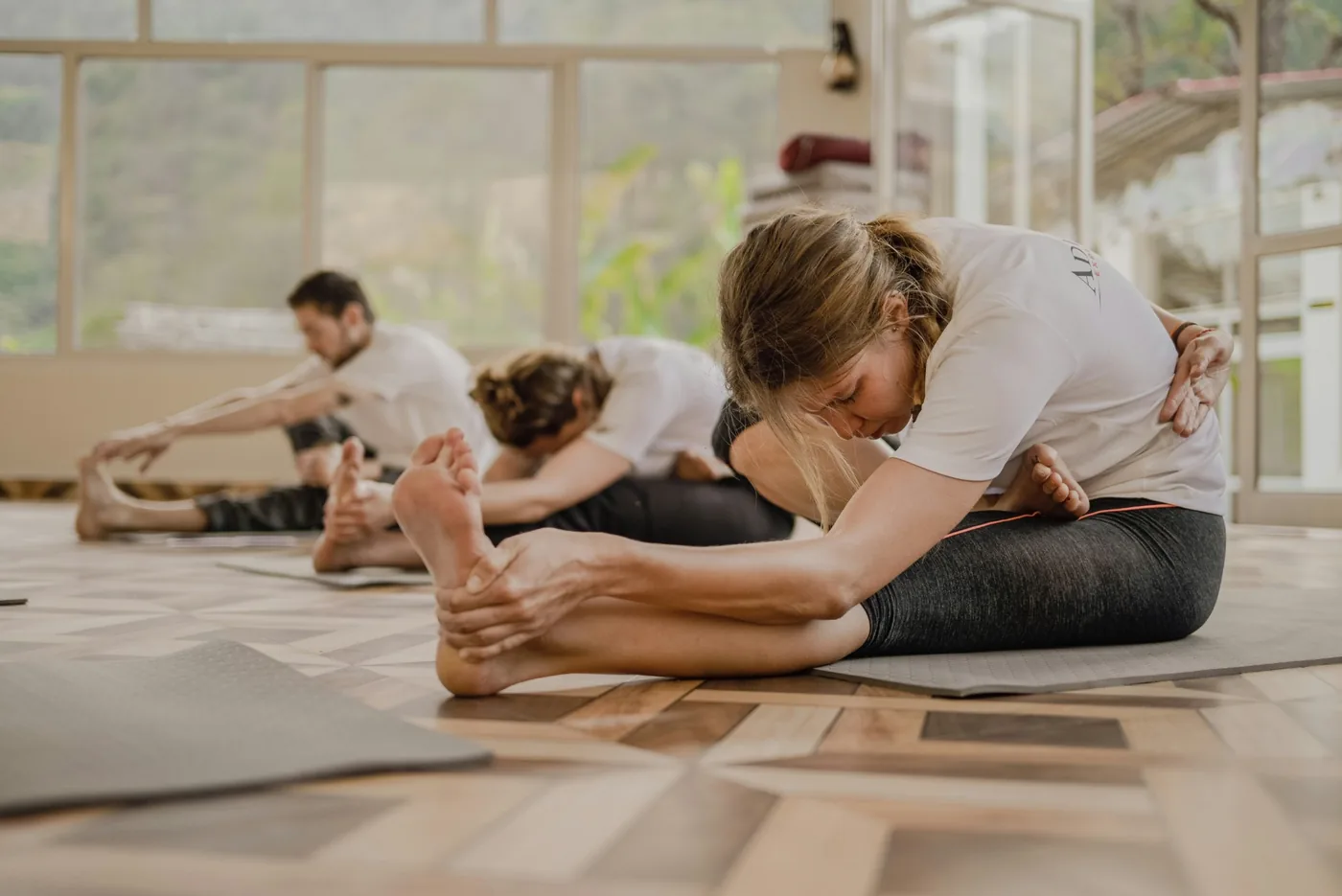 Group Pilates class practicing seated forward folds