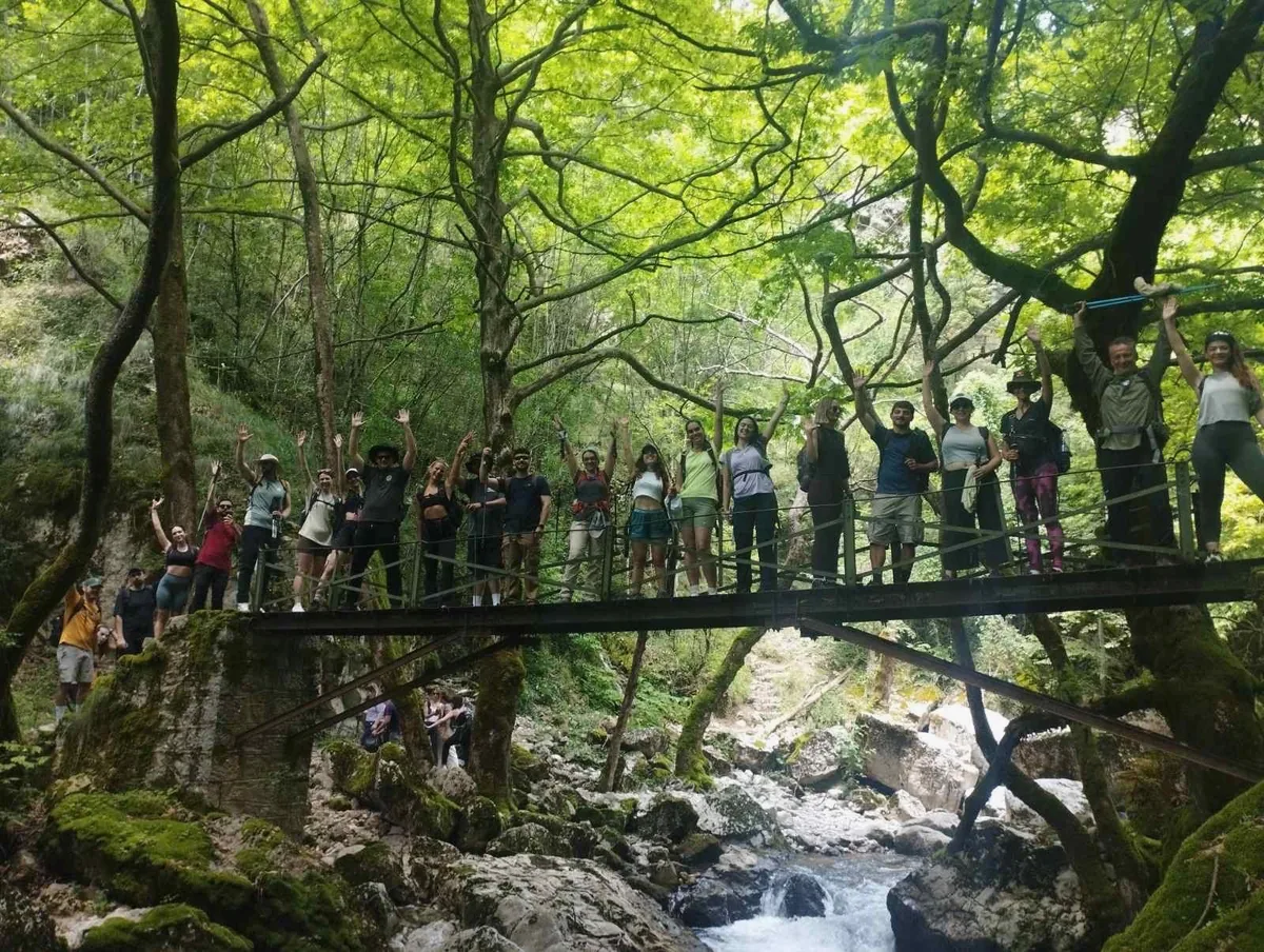 The group waving from a footbridge over the river